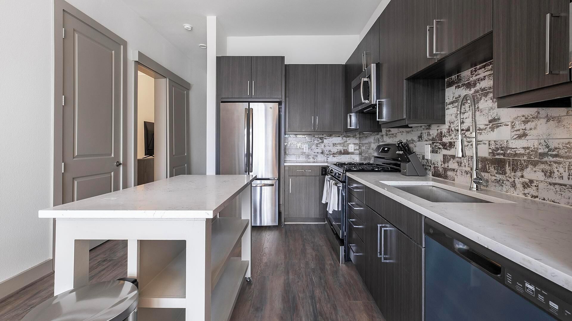 Une cuisine moderne avec des meubles en bois foncé, des appareils électroménagers en acier inoxydable et un plan de travail en marbre.