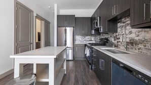 A modern kitchen with dark wood cabinets, stainless steel appliances, and a marble countertop.