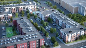 Ein moderner Apartmentkomplex mit mehreren Gebäuden, Parkplätzen und Grünflächen.