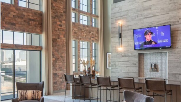 Un hall d’entrée spacieux avec un grand écran de télévision, des murs en briques et un bar au design moderne.