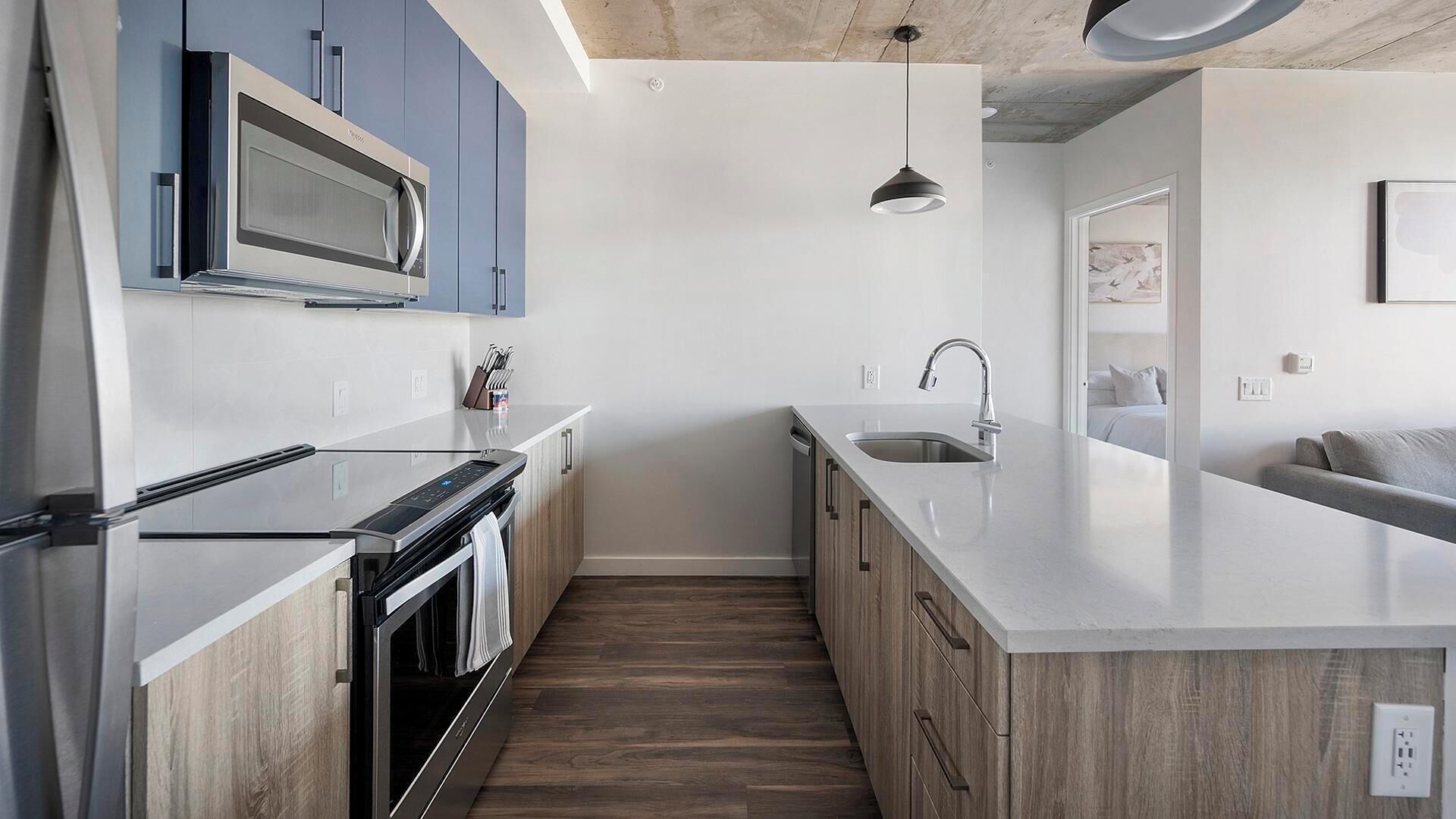 Una cocina moderna con horno empotrado, microondas y lavamanos.