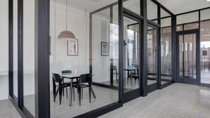 Ein modernes Interieur mit Glaswänden, einem Essbereich mit Stühlen und einer Deckenleuchte.