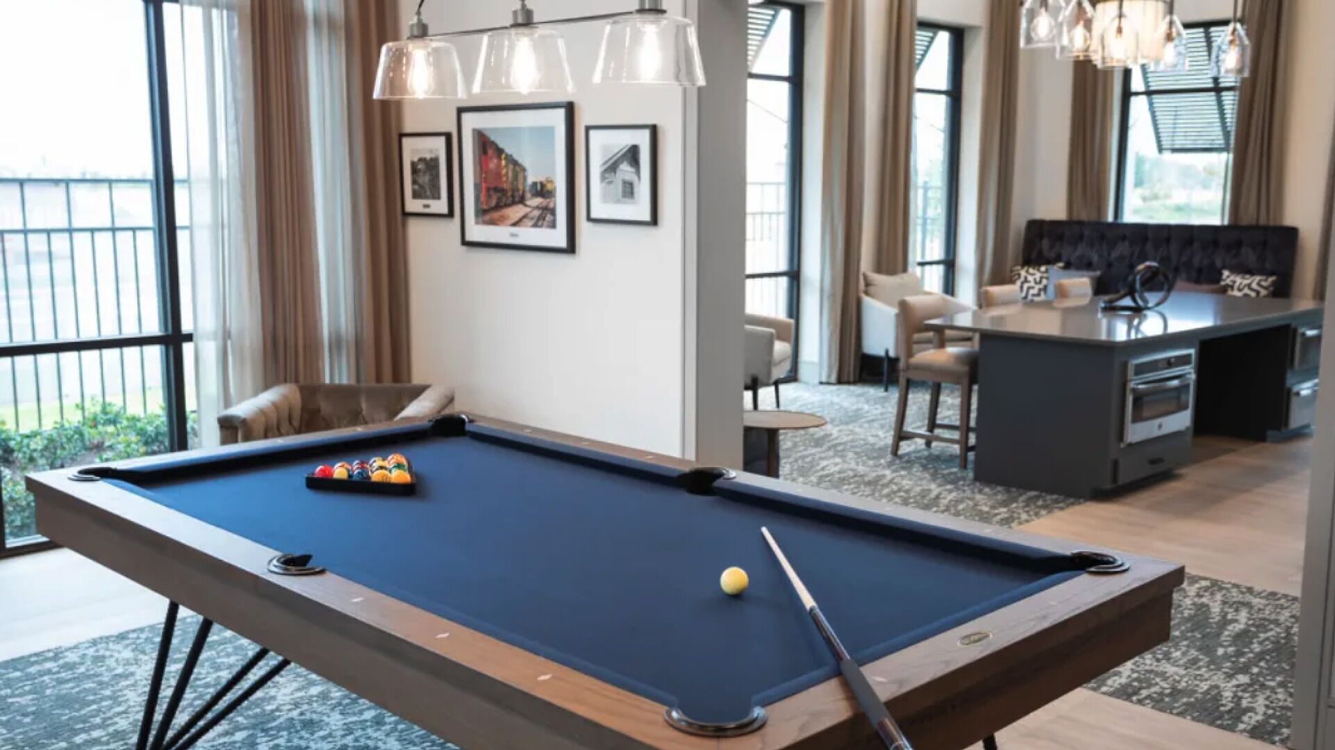 Une table de billard avec des billes, un bar et un espace détente avec des chaises.