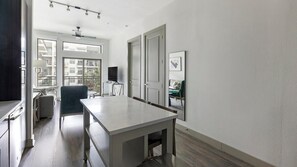 Une cuisine moderne dotée d’un grand îlot central, d’un coin repas avec une table et des chaises, et offrant une vue sur la ville grâce à de grandes fenêtres.
