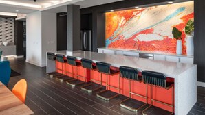 Une cuisine moderne dotée d’un coin bar, avec un grand îlot central agrémenté de tabourets et d’un revêtement mural coloré.