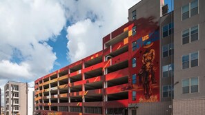 Un parking à plusieurs étages dont l’une des façades est ornée d’une fresque représentant une figure historique.