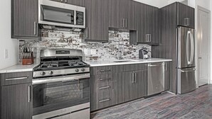 Une cuisine moderne avec des meubles en bois foncé, des appareils électroménagers en acier inoxydable et un dosseret carrelé.