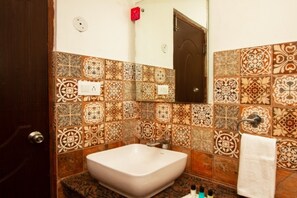 A bathroom with a large, square sink and a mirror above it. The walls are decorated with patterned tiles. - The Spruce Mansion Manali (Manali)