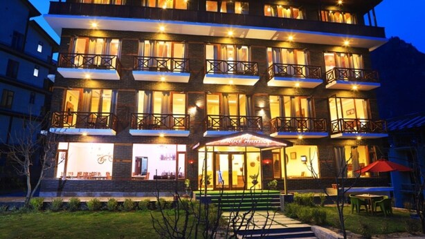 A multi-story hotel with balconies, a restaurant, and a well-lit entrance. - The Spruce Mansion Manali (Manali)