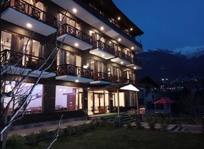 A multi-story hotel with balconies and a well-lit entrance. - The Spruce Mansion Manali (Manali)