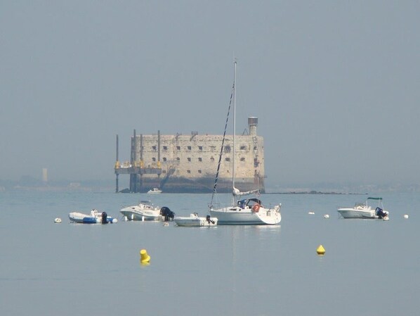 A marina with several boats docked, a large building in the background, and a clear sky.