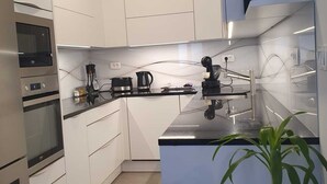 A modern kitchen with white cabinets, a built-in oven, a coffee machine, and a potted plant. - Cozy 1-bedroom apartment with WiFi, AC in enjoyable Ljubljana (Ljubljana)