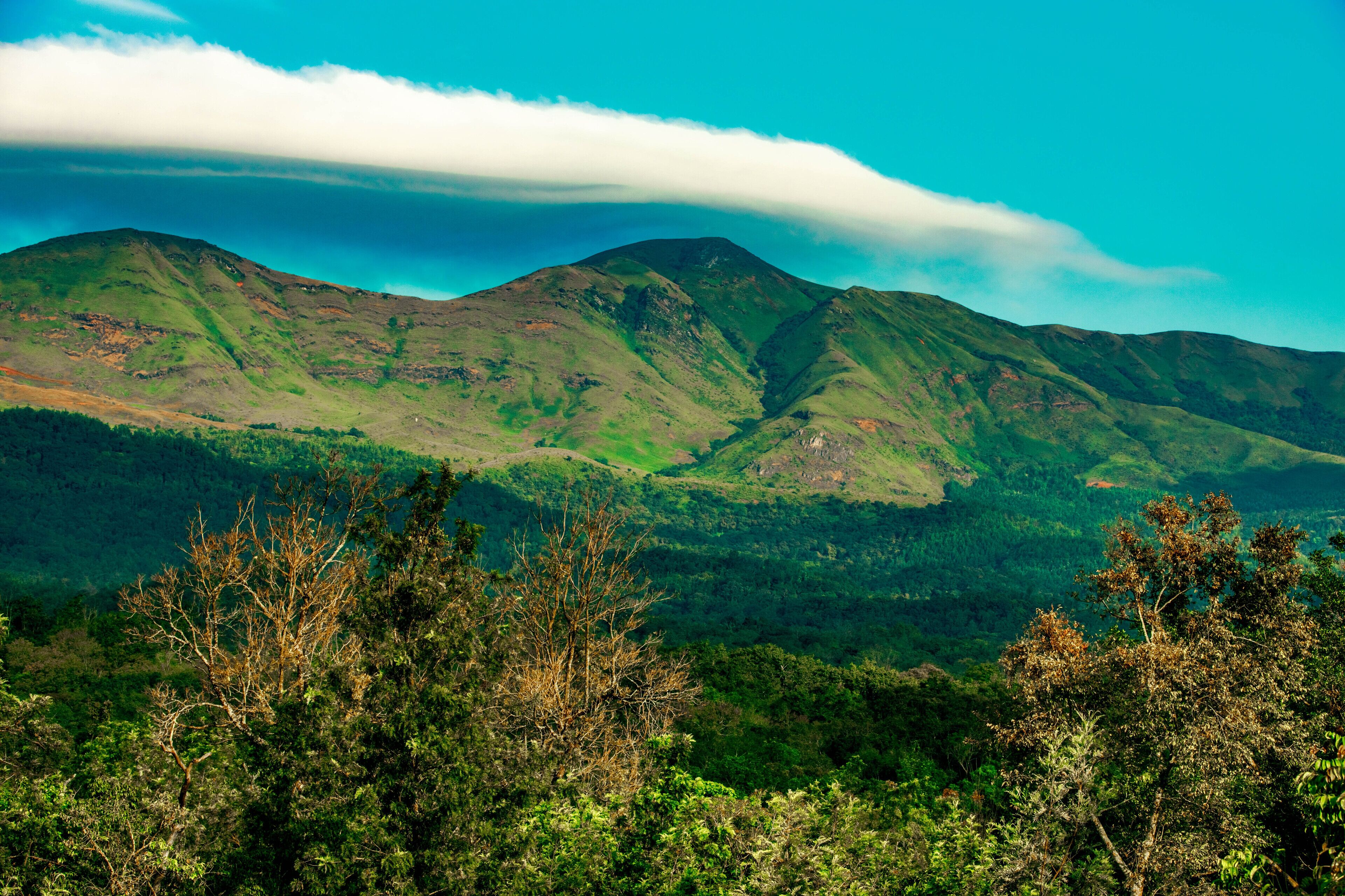 A mountainous landscape with lush greenery and a prominent cloud formation.