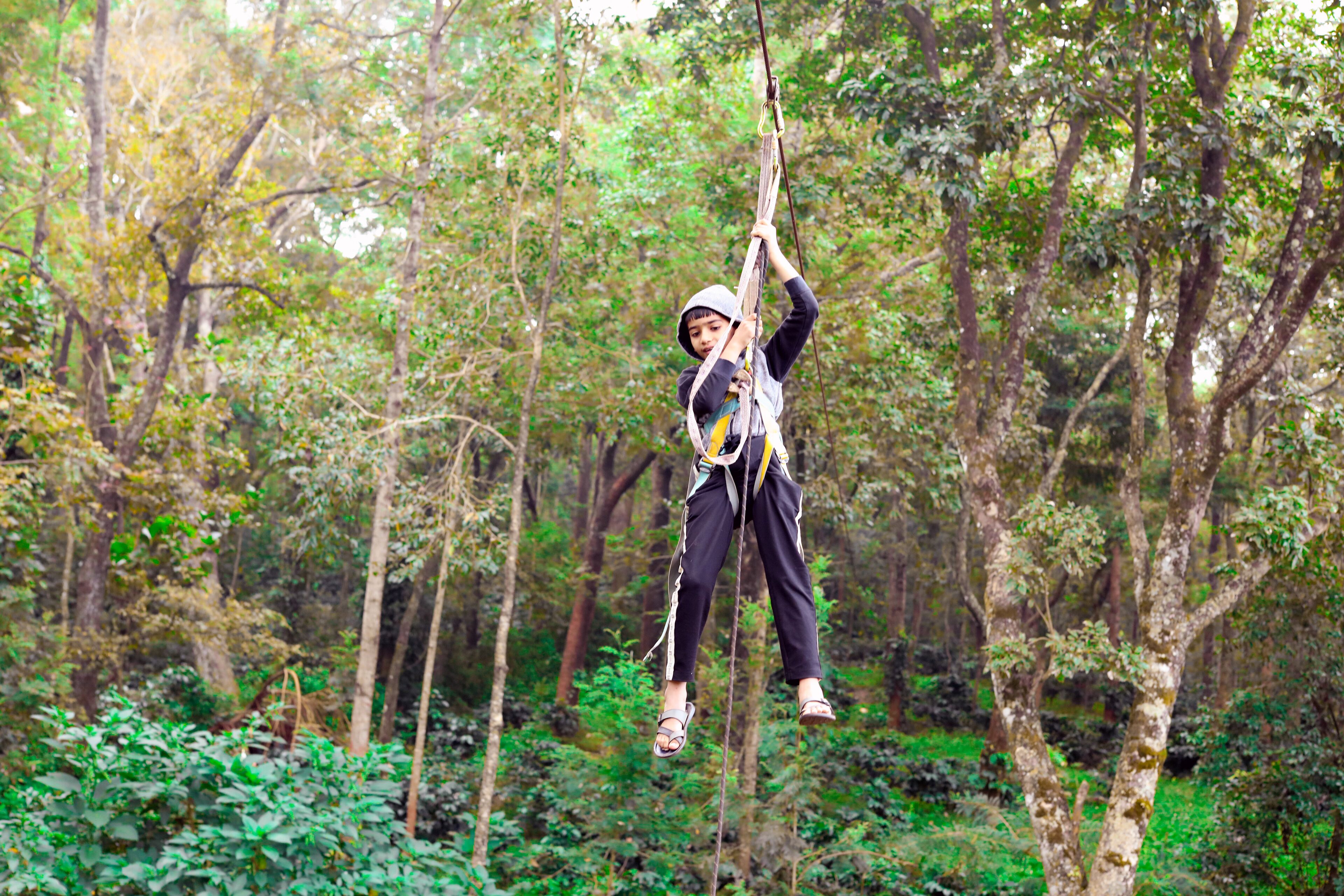 Una persona colgada en un bosque, agarrada a una cuerda.