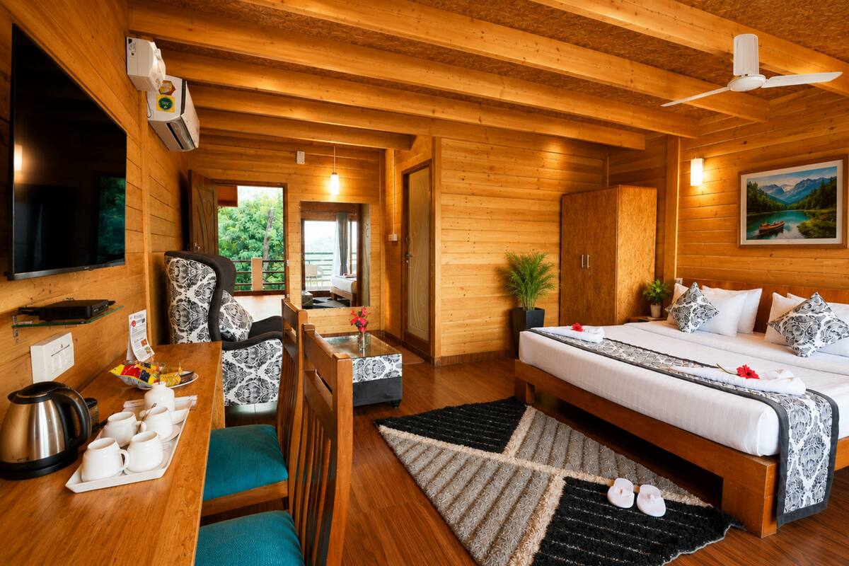 Une pièce aménagée comme un chalet en bois, avec un lit, une table à manger, des chaises, un coin café et un téléviseur.