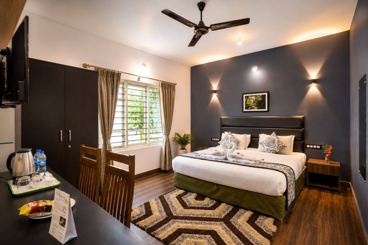 Une chambre d’hôtel moderne équipée d’un lit, d’un bureau, d’une télévision, d’un ventilateur de plafond et d’une fenêtre avec des rideaux.