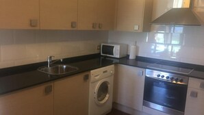Eine kleine Küche mit Waschmaschine, Mikrowelle und Backofen.