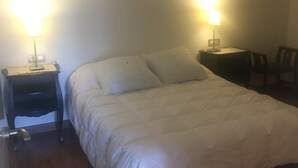 Einzimmerappartement mit einem Bett, zwei Nachttischen und zwei Wandleuchten.