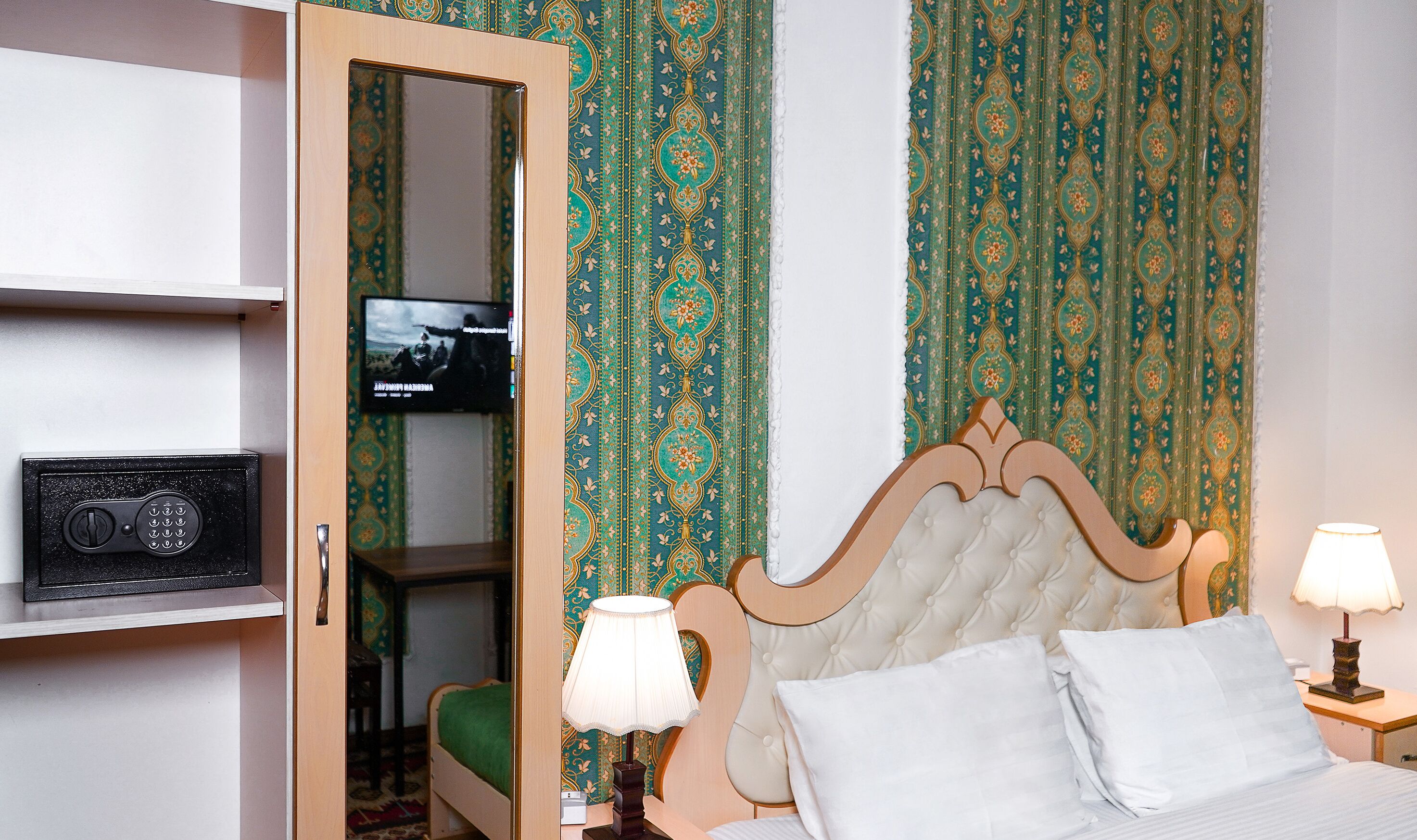 Habitación de hotel con una cama, dos lámparas de noche, un televisor en un estante y una radio.