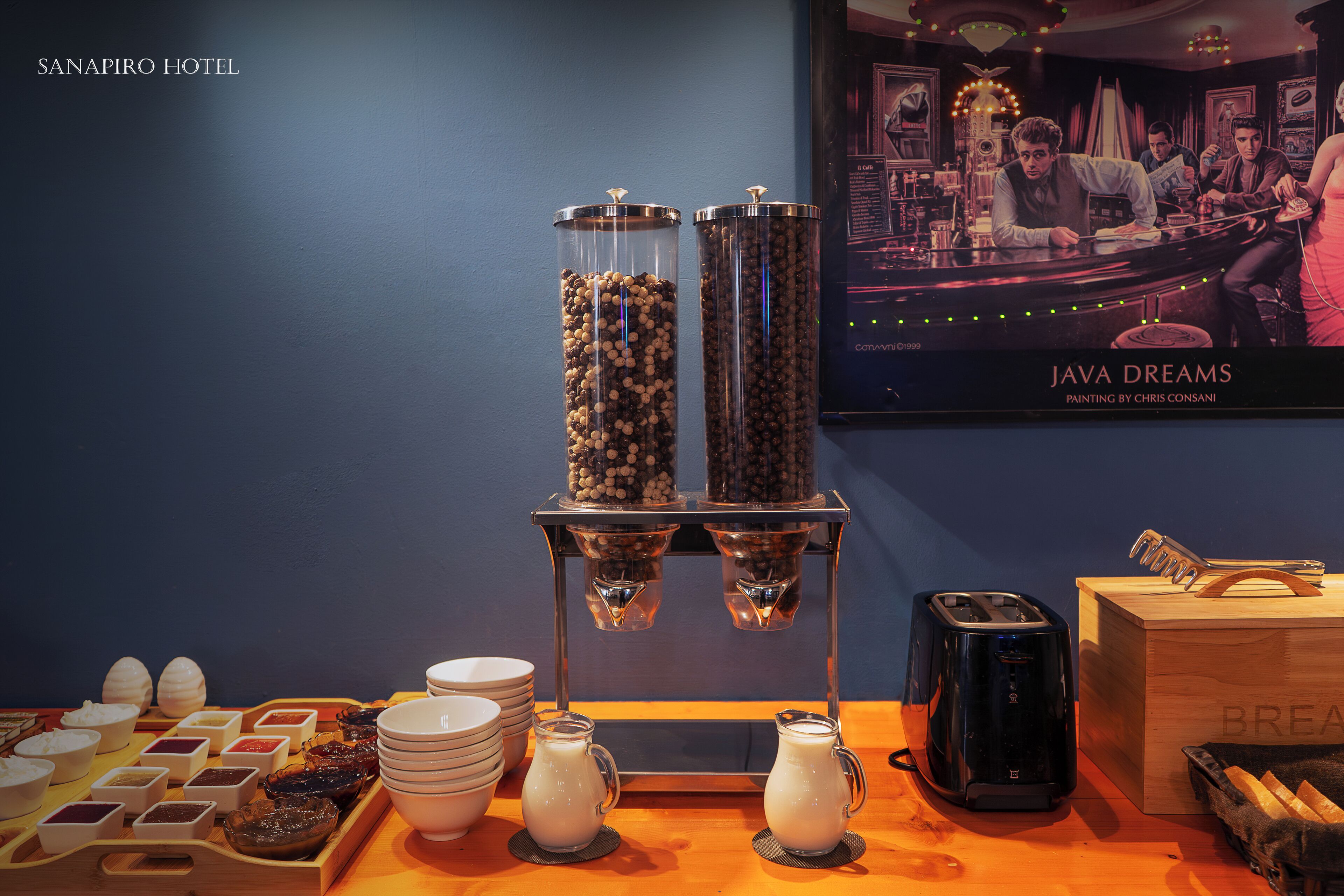 Montaje de desayuno buffet con granos de café, jarras de leche y un tostador.