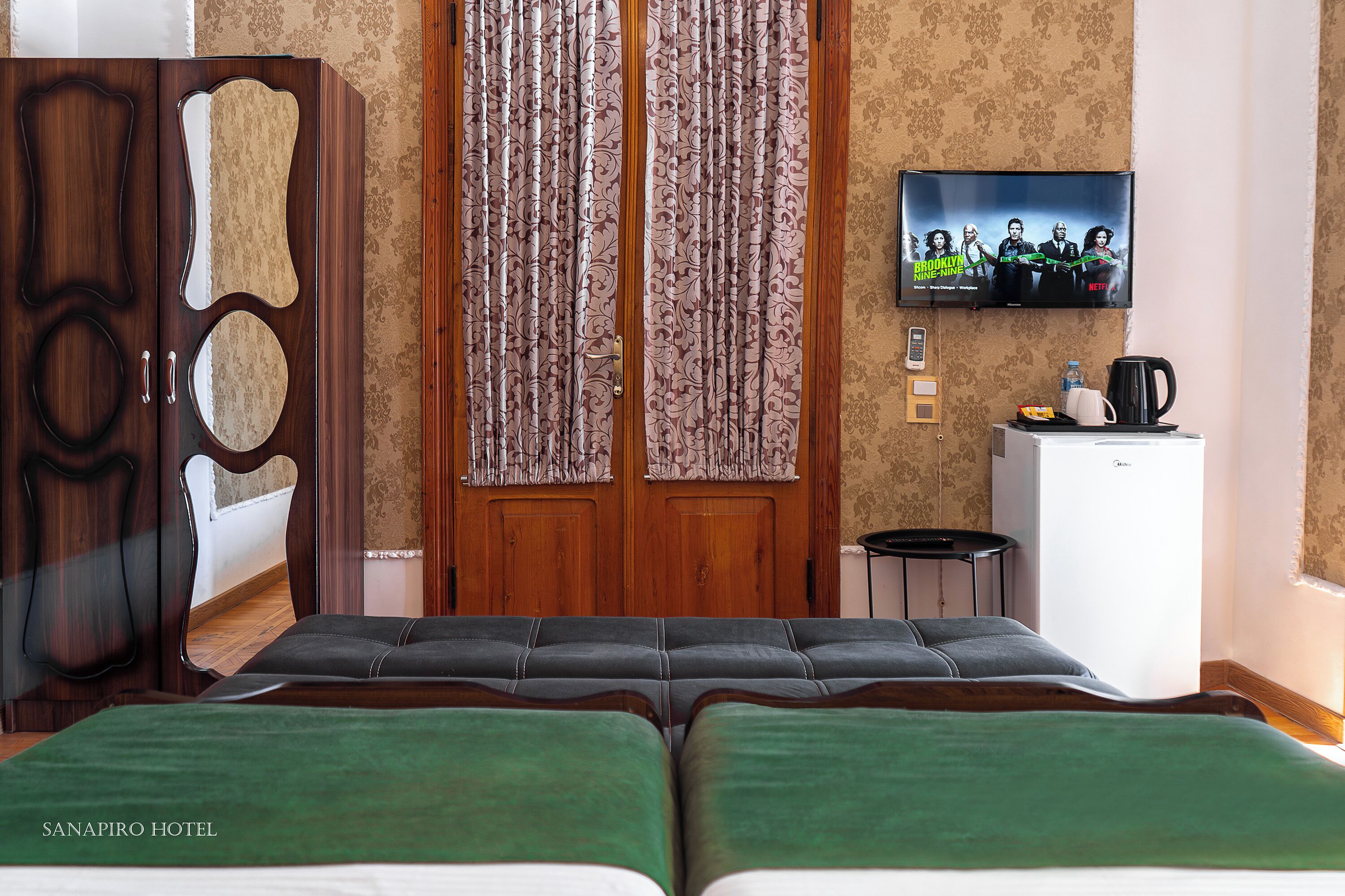 A hotel room with a bed, a TV, a desk, and a wardrobe.