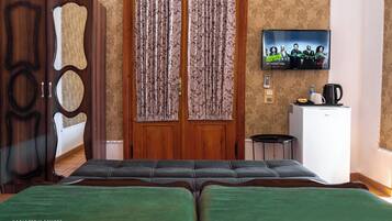 A hotel room with a bed, a TV, a desk, and a wardrobe.
