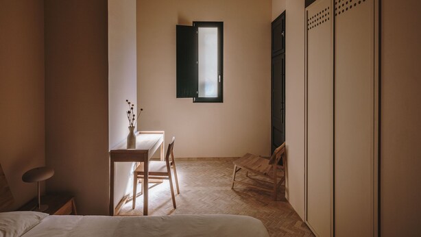 Un dormitorio con cama, escritorio, silla, ventana y armario.
