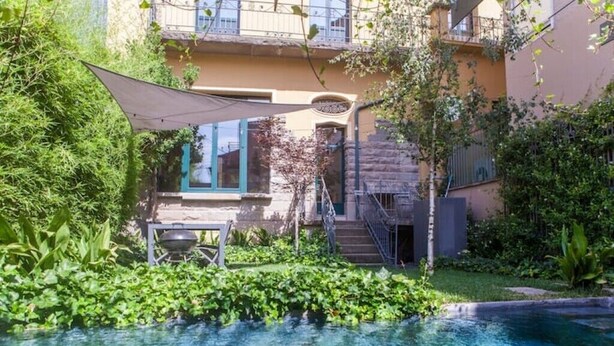 A residential building with a swimming pool, surrounded by lush greenery and a patio area. - Antigua Fábrica Descals, Edificio Histórico (Olot)