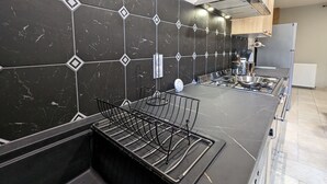Une cuisine moderne avec des carreaux de marbre noir, des appareils en acier inoxydable et un four encastré.