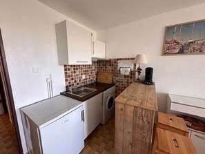 Una cocina funcional con lavadora, lavamanos y encimera de madera.