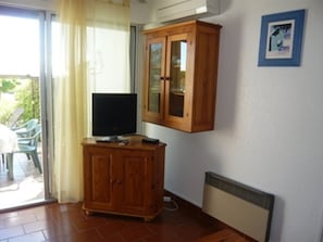 A room with a wooden cabinet, a television, and a framed picture on the wall.