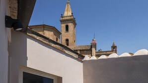 A rooftop terrace with a clear view of a historic building with a bell tower.