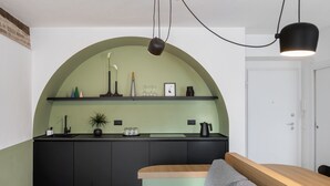 A modern kitchen with a curved arch, a wooden bench, and a grey sofa.