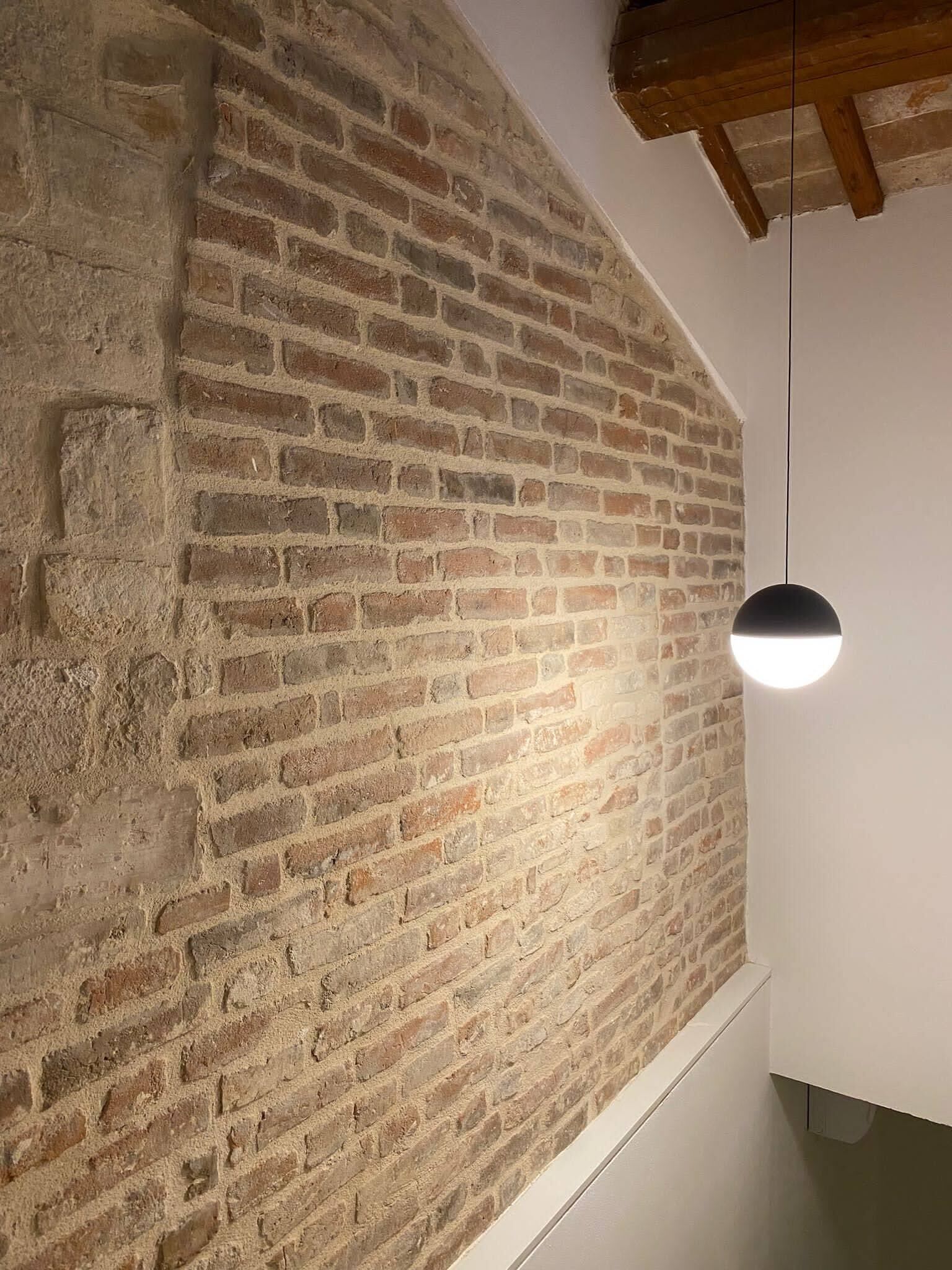 Une pièce aux murs en briques apparentes et dotée d’un luminaire suspendu moderne.