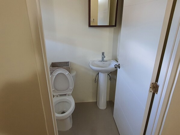 Un baño pequeño y funcional con inodoro, lavamanos y espejo.