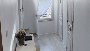 Ein schmaler Gang mit einer hölzernen Bank, einem kleinen Tisch mit einer Vase und einer Deckenleuchte.