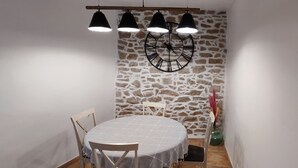 Ein Essbereich mit einem runden Tisch, drei Pendelleuchten und einer Steinwand.