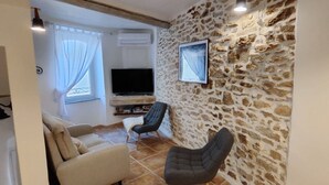 Ein Wohnzimmer mit Steinwand, Flachbildfernseher, Sofa und Sessel.