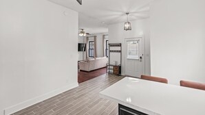 A modern interior with a dining area, a sofa, and a staircase leading to another level. - Cozy Duplex Near DT, King, 3 TVs, Walk To Dine (Columbia)