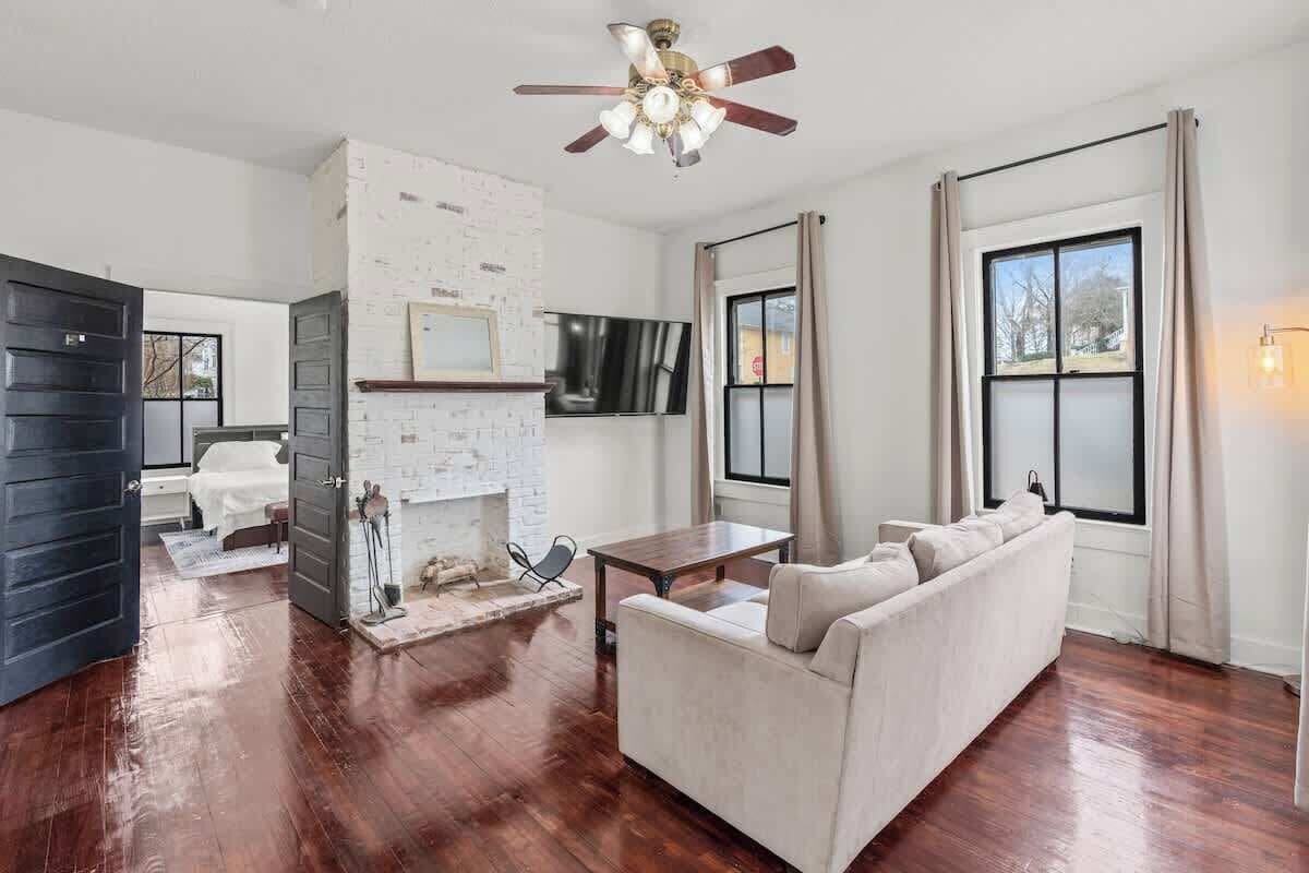 A living room with a fireplace, a sofa, a TV, and a ceiling fan.
