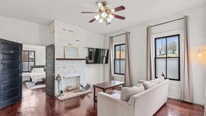 A living room with a fireplace, a sofa, a TV, and a ceiling fan. - Cozy Duplex Near DT, King, 3 TVs, Walk To Dine (Columbia)