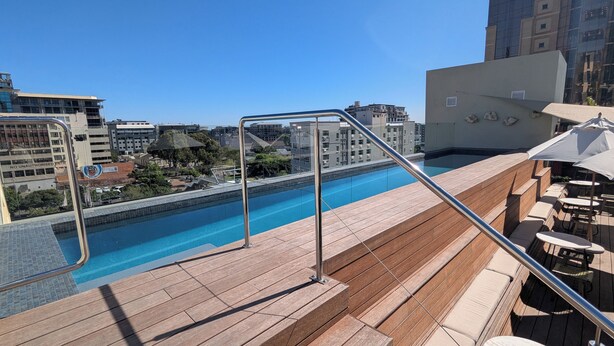 A rooftop pool with wooden deck and metal railings, surrounded by urban buildings. - Trendy Studio at the Barracks on Bree (Cape Town)