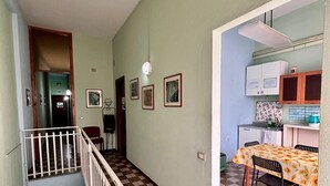 Eine Treppe führt zu einer zweiten Etage, einem Essbereich mit Tisch und Stühlen sowie einer Küche mit Schränken und einer Arbeitsplatte.