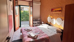 Ein Schlafzimmer mit einem Bett, einem Schreibtisch und einem Stuhl. Ein Fenster bietet Blick auf Grünflächen.