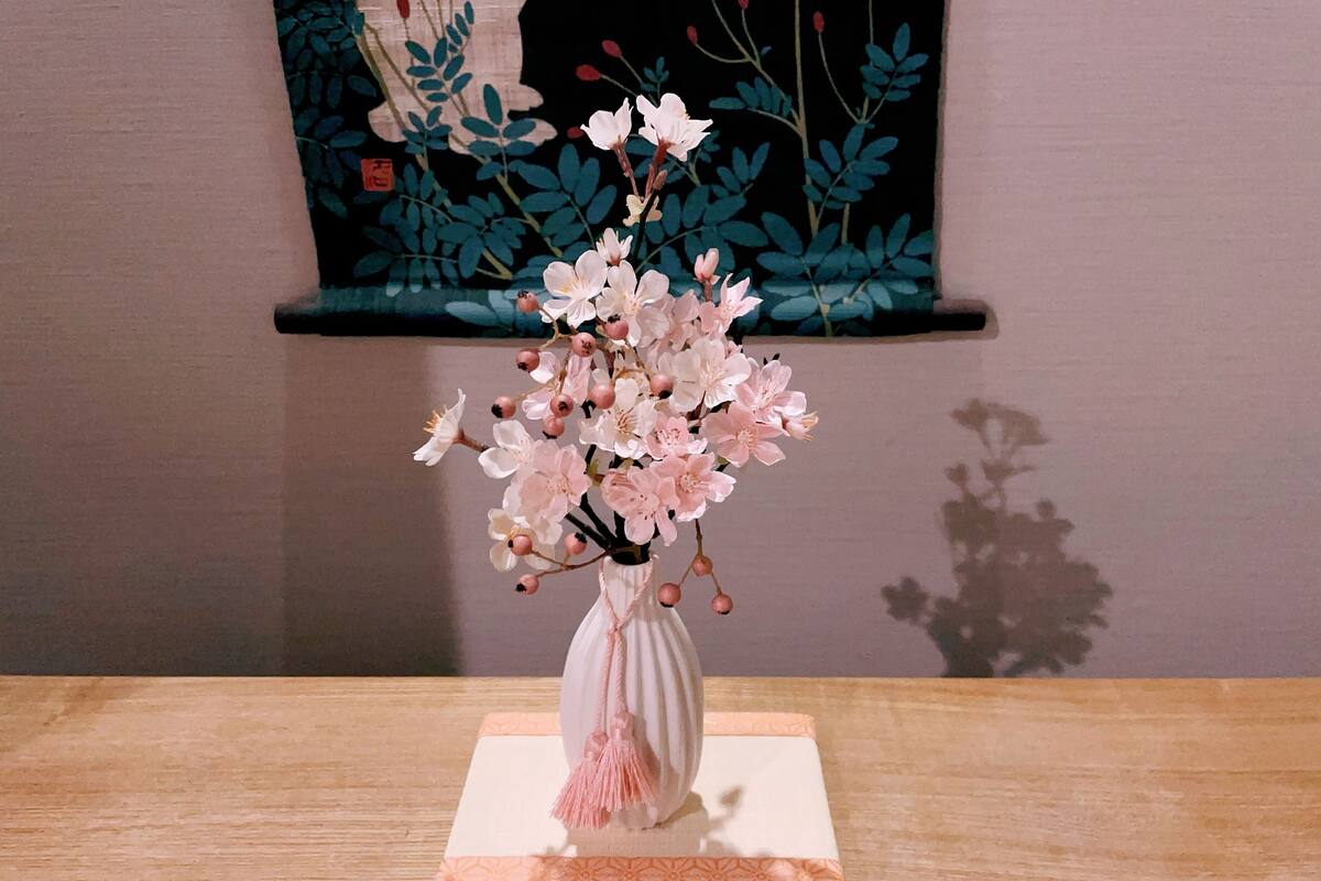 A vase with pink flowers on a wooden table.