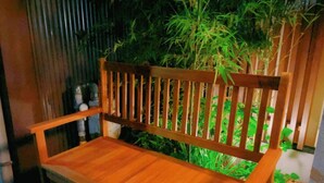 A wooden bench with a slatted backrest and armrests, positioned in front of a bamboo fence. - suikakan heianjingumae (Kyoto)