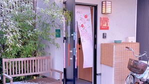 A wooden bench, a bicycle, and a door with a floral curtain. - suikakan heianjingumae (Kyoto)