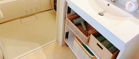 A bathroom with a bathtub, a sink with toiletries, and storage baskets.