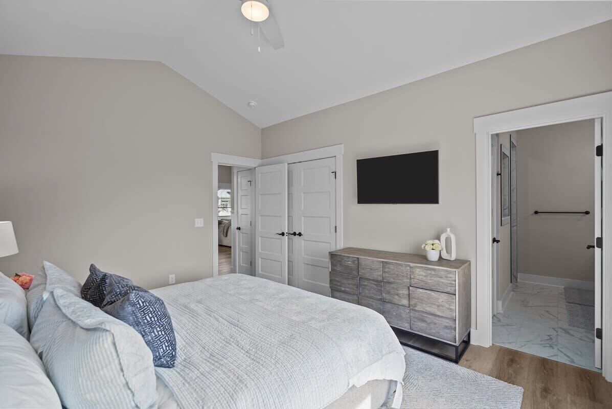 A bedroom with a bed, dresser, and a TV on the wall.