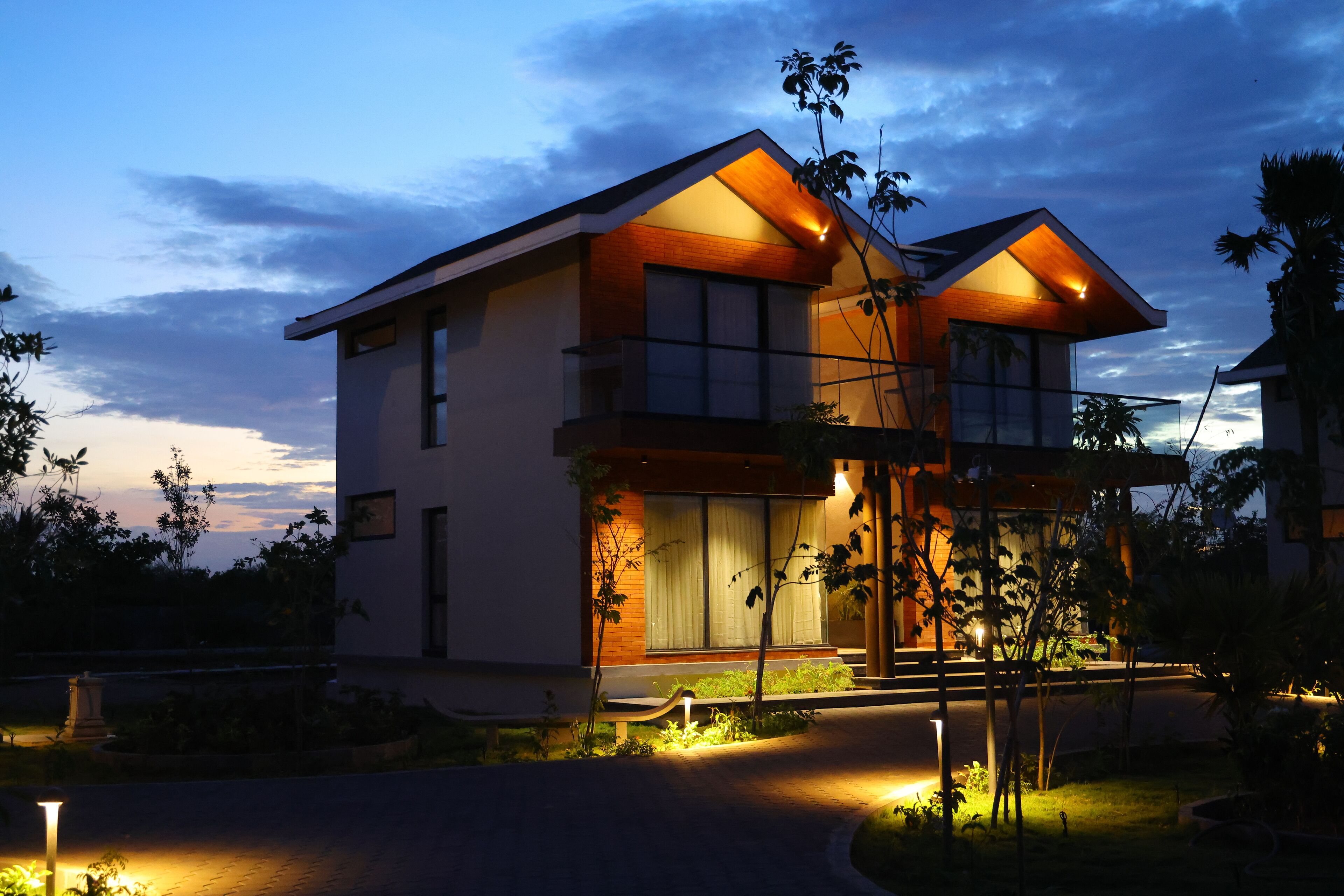 A modern two-story house with a well-lit entrance and a landscaped garden.